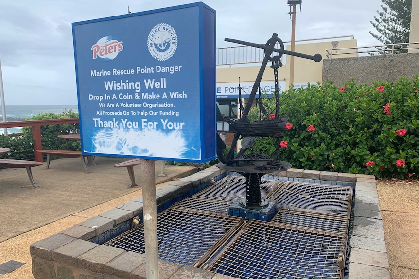 Marine rescue donation sign in front of wishing well featuring an iron anchor and miniature ship sculpture at Point Lookout