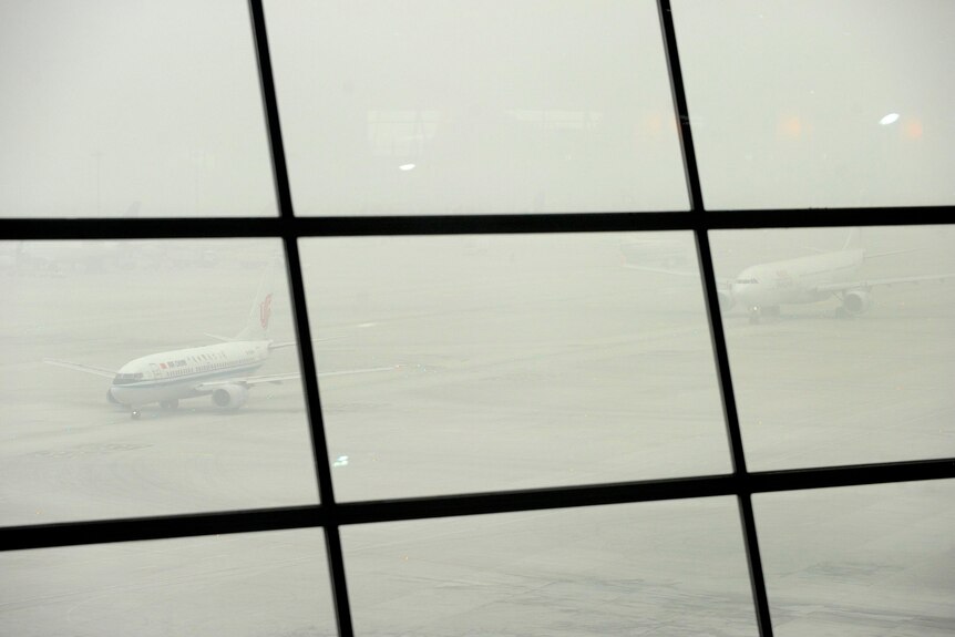 Aeroplanes queue to take off at Beijing International Airport while shrouded in smog.