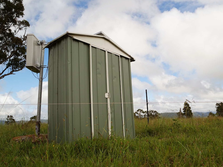A green shed in a paddock on a cloudy day