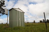 A green shed in a paddock on a cloudy day