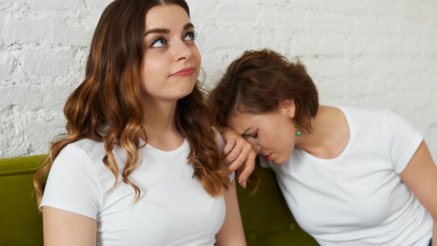 Friend rolling eyes as friend leans on her shoulder crying
