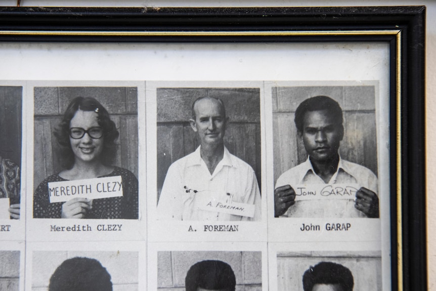 A frame containing black-and-white passport-type portraits of people, including a middle-aged white man in the centre.