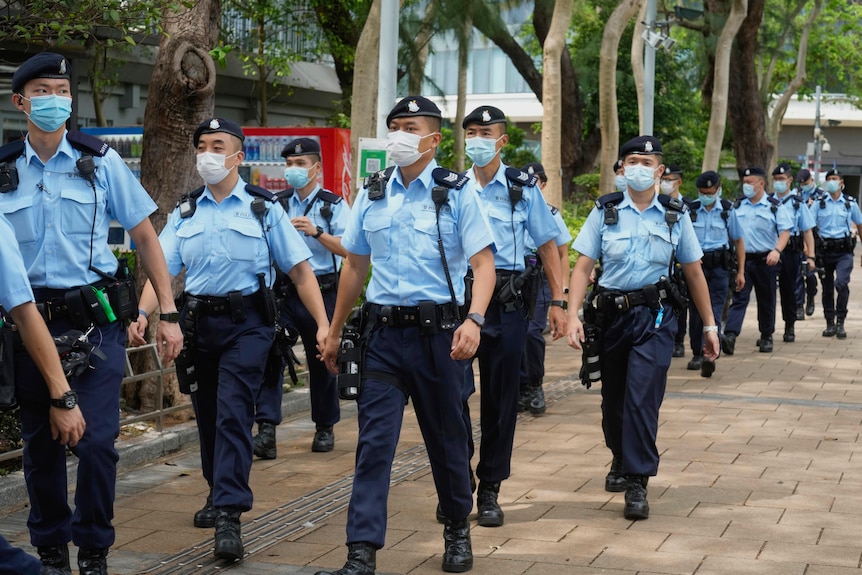 Dozens of uniformed Hong Kong police officers march down the street