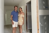 Dylan Farqhuar and Tylah Ingram standing in their house mid-renovation, there are no doors and the walls haven't been painted
