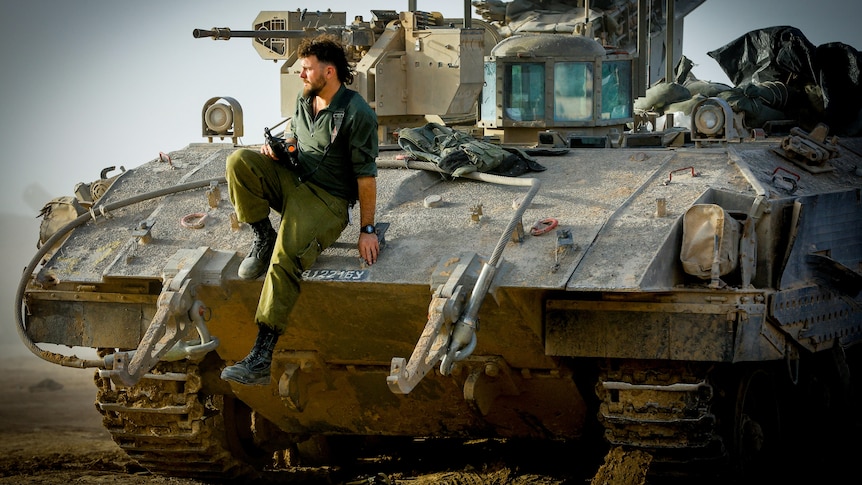 A soldier sitting on the edge of a tank