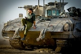 A soldier sitting on the edge of a tank