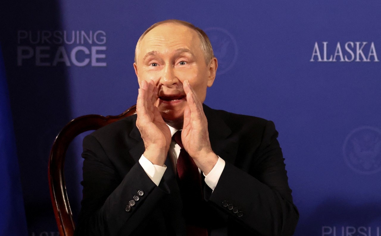 Um homem de terno colocando as mãos perto da boca e falando