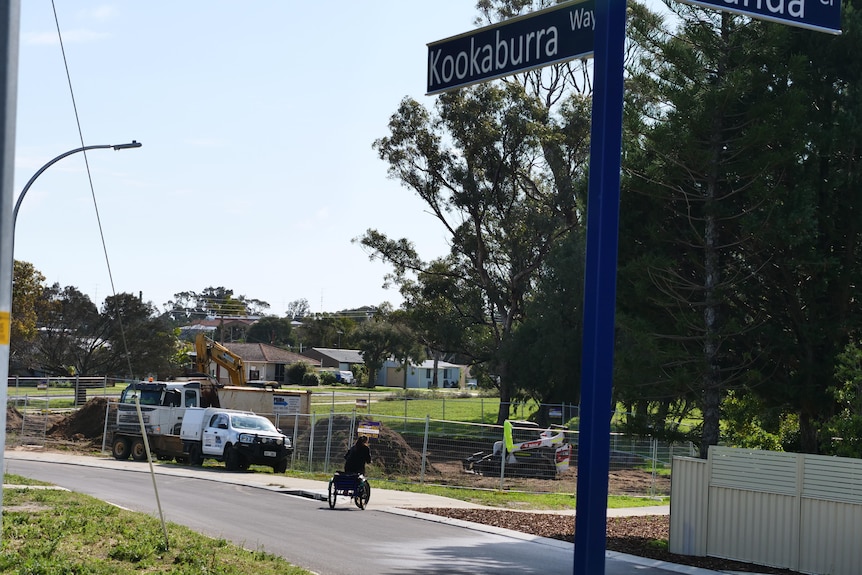 Someone riding a bike down a road that is signed as Kookaburra Way.