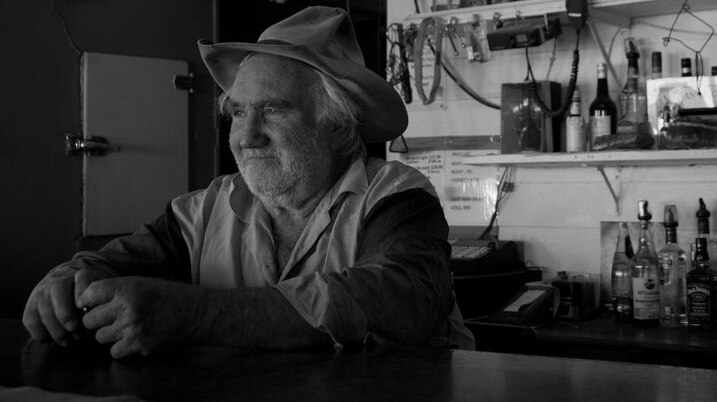 Black and white photo of publican Lester Cain sitting at the bar at the Middleton Hotel in outback Queensland.