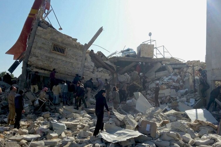 People walk near a ruined building in Syria.