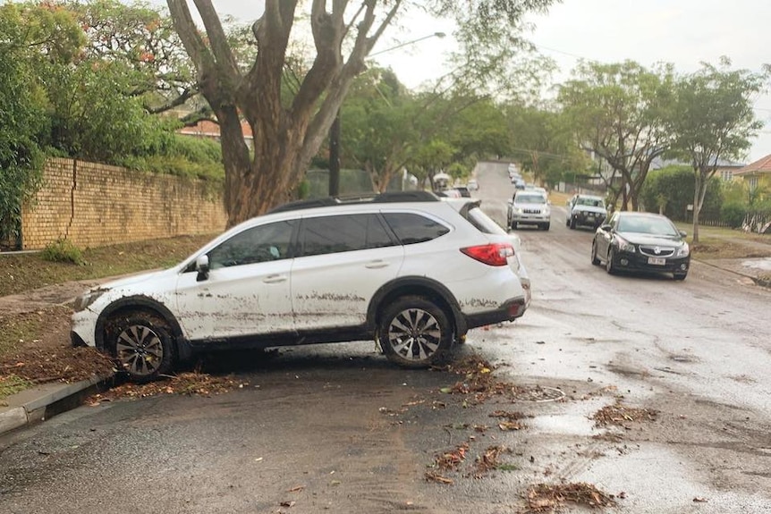 A vehicle is horizontal to the curb and covered in mud after flash flooding on the southside.