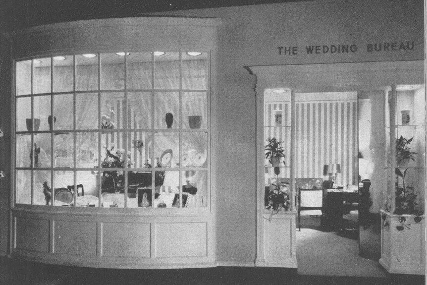 A black and white image of a shopfront with a big window and 'the wedding bureau' written above the door.
