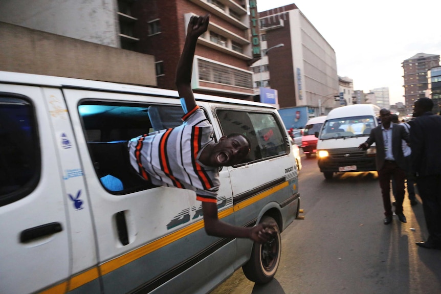 Man celebrating hangs out a van window in Zimbabwe