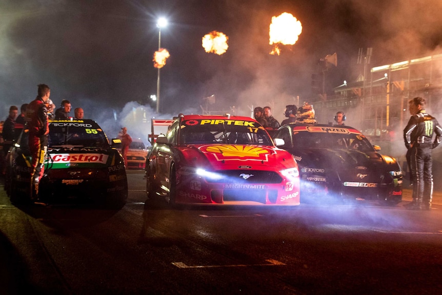 Three V8 Supercars line up at the race starting line.