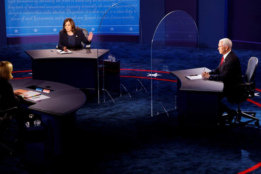 Kamala Harris and Mike Pence sitting behind plexiglass shields separating their desks on the debate stage