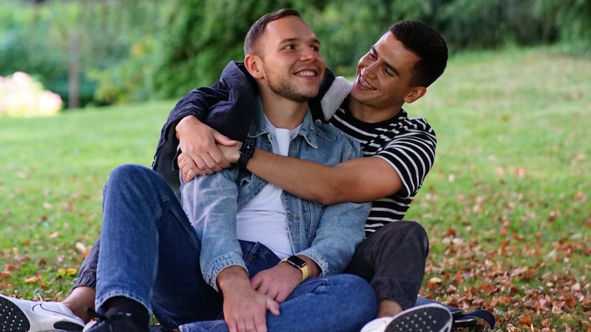 Vladyslav Guz and his boyfriend sit in the park. They fled the war in Ukraine.