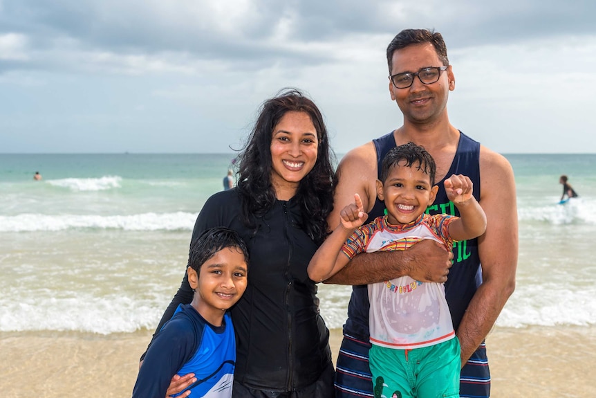 Monika and Vineet Manot and their sons' Aarav,8, and Anay,4 pose for a photo in the water at Mooloolaba Beach.