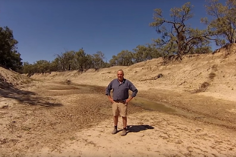 Lower Darling River farmer Rob McBride shows the dry river bed of the Lower Darling River