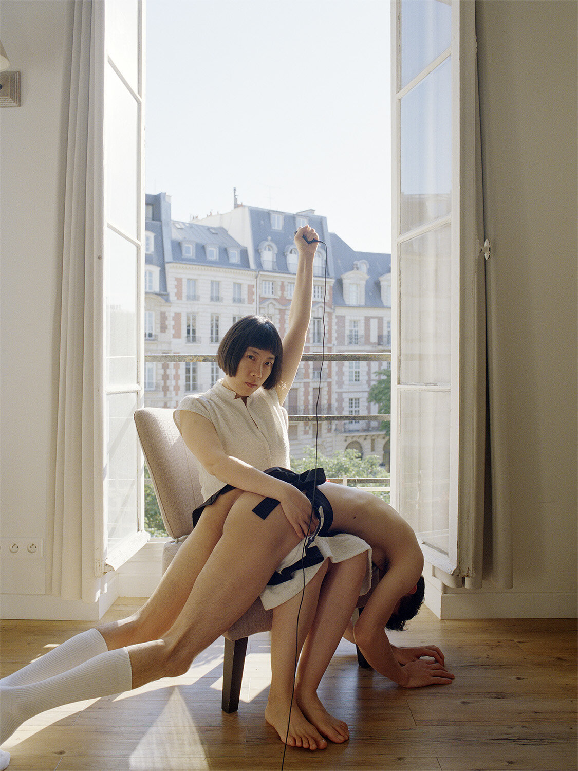 Pixy Liao, a 30-something Chinese woman with short dark hair holds a camera shutter remote with a semi-nude man on her lap.