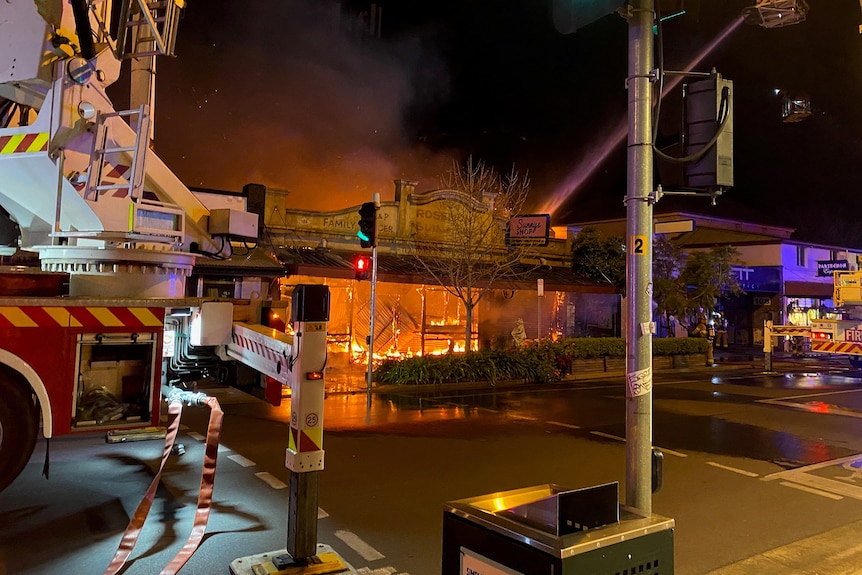 A shopfront burns with a fire truck in the foreground