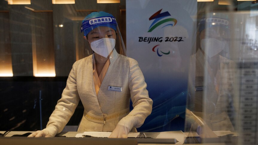 Woman in PPE behind a kiosk desk.