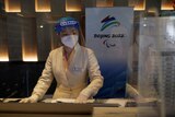 Woman in PPE behind a kiosk desk.