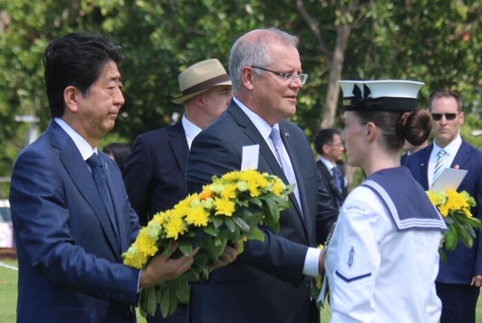 Shinzo Abe and Scott Morrison hold wreaths in a park