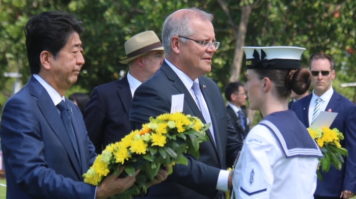 The pair hold wreaths in a park