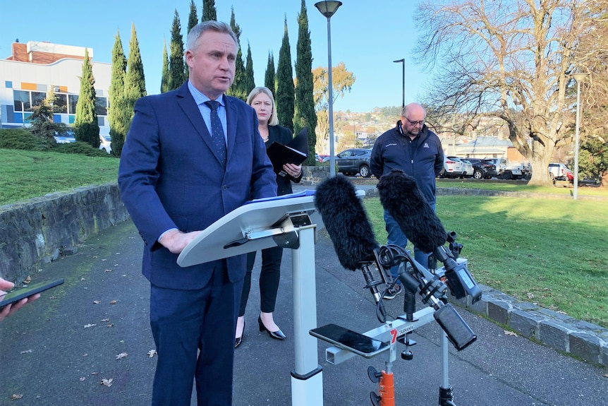 Three people at a press conference outside.