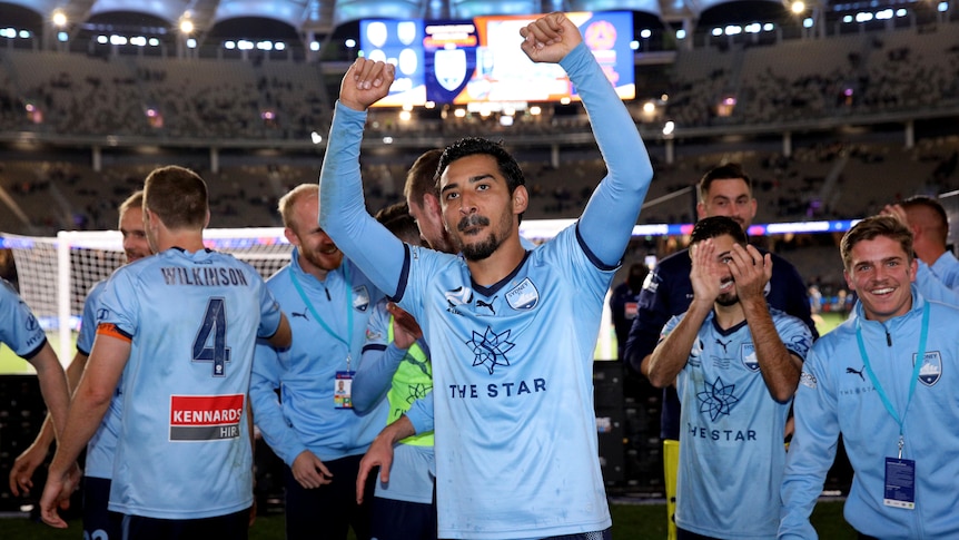 A group of Sydney FC players raise their hands towards fans after winning the grand final