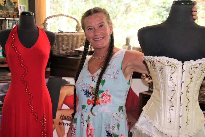 Leah Kelly standing in the center of two dresses on display