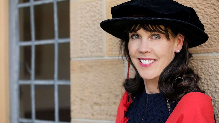 A woman smiles for the camera in an academic gown