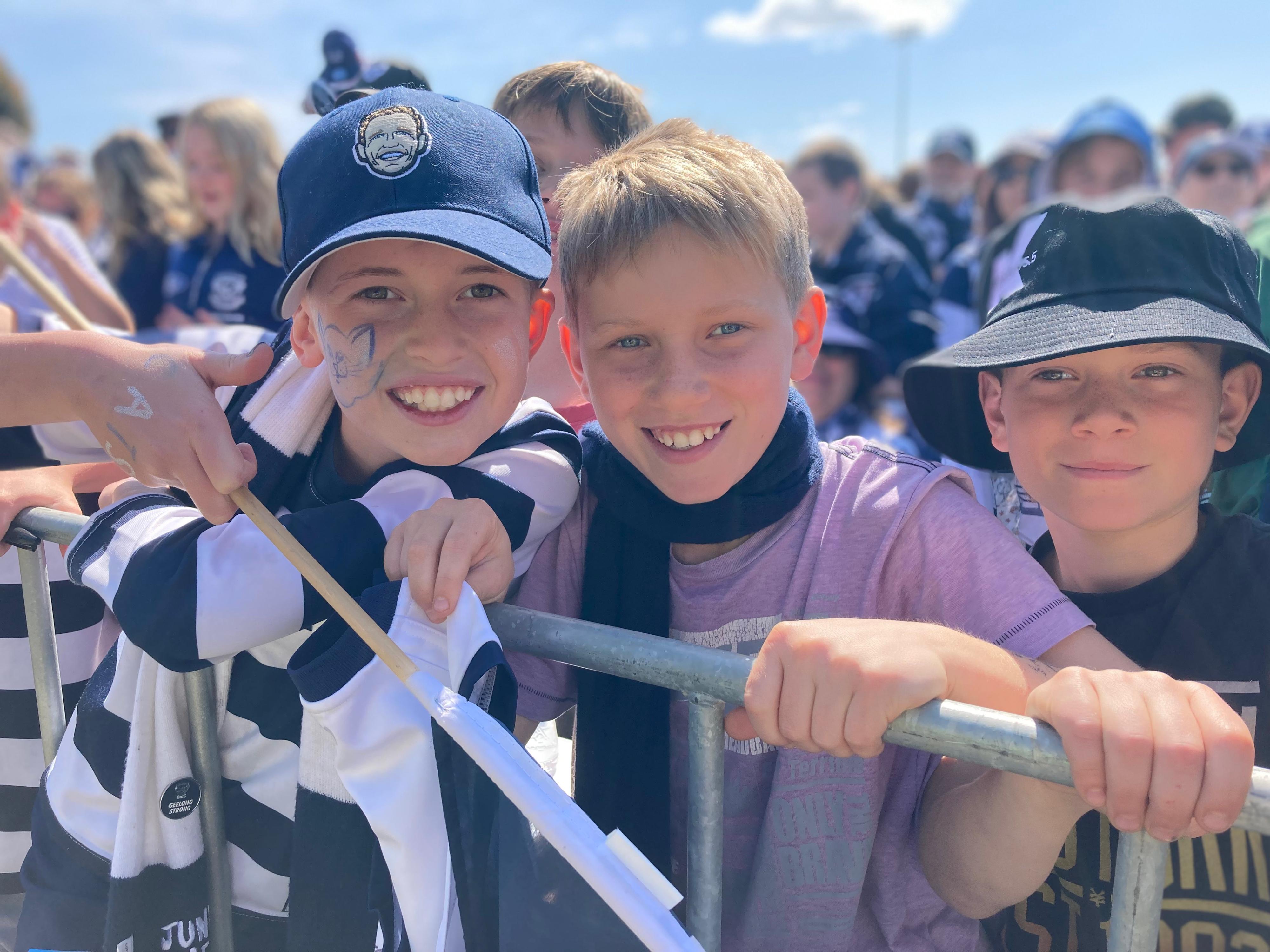 Cas Kovac and his friend smile in the sunshine, dressed in their blue and white Geelong team colours.