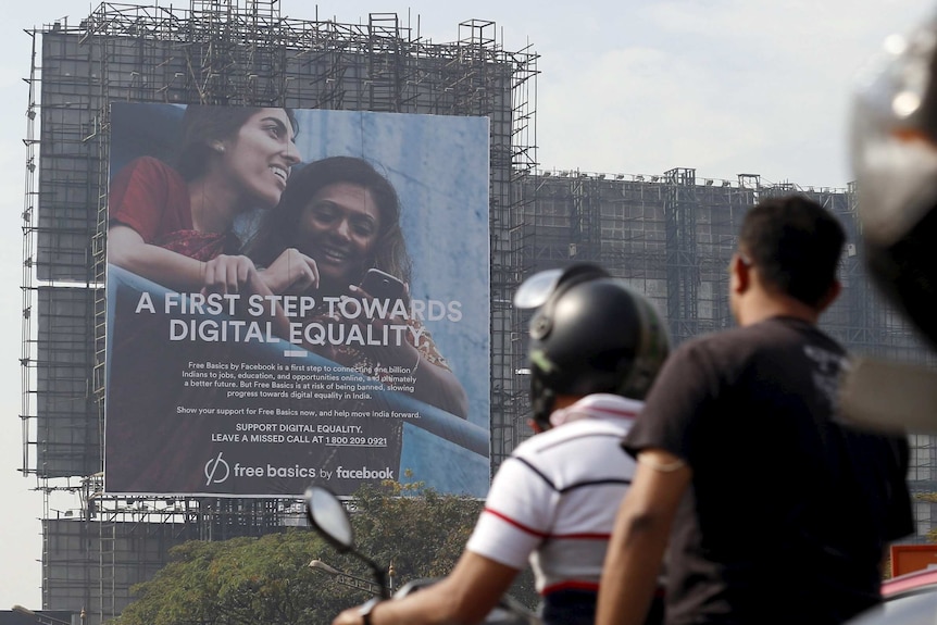 Motorists ride past a billboard displaying Facebook's Free Basics initiative in Mumbai.