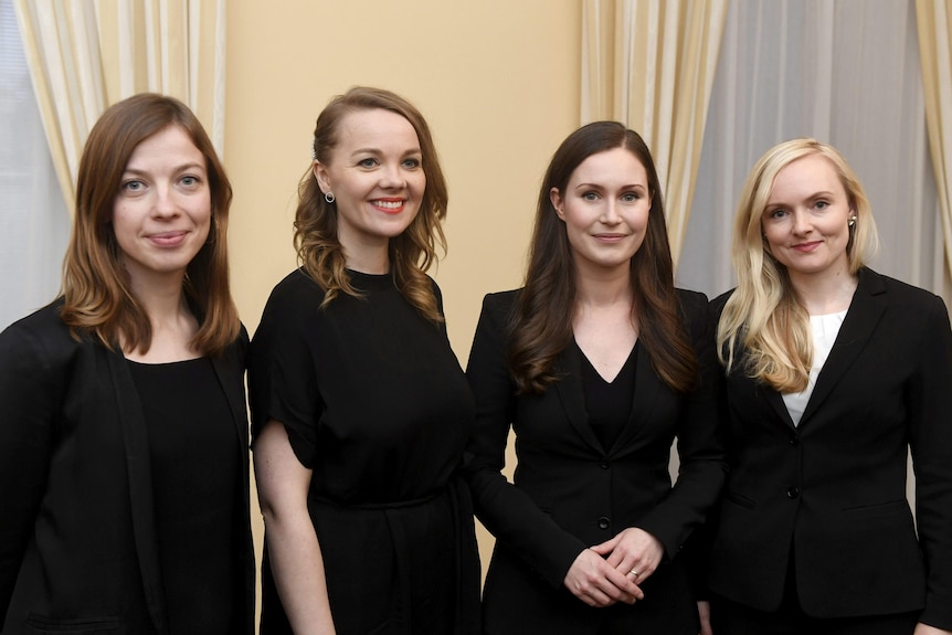 Four women wearing black, including Sanna Marin in the middle, stand smiling at a camera.