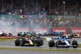 Formula 1 cars drive with a crash happening in the background