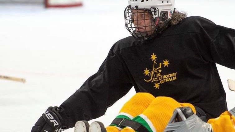 Australian Para-ice hockey athlete Darren Belling competing in a game at an ice rink, wearing a helmet with a go-pro camera.
