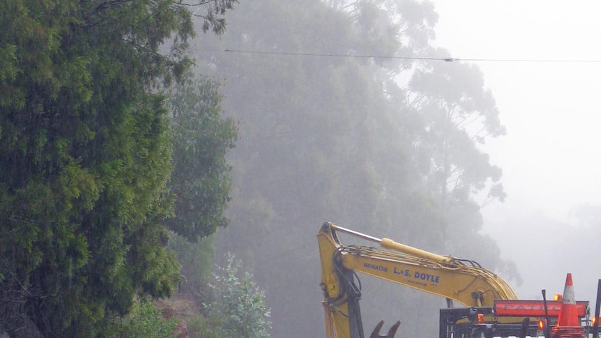 Workers clear a landslip caused by heavy rain on Channel Highway south of Snug, Tasmania.