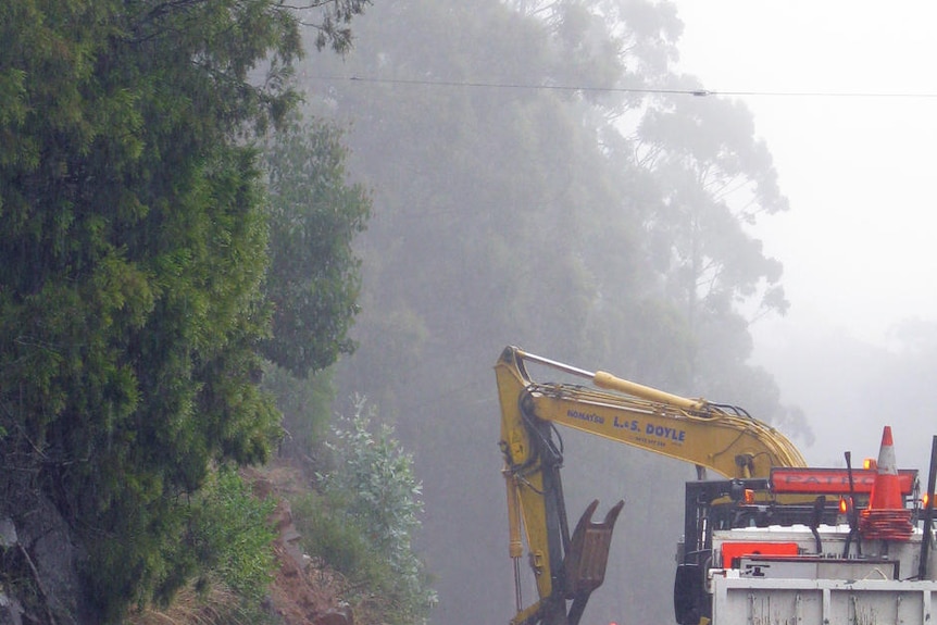 Workers clear a landslip caused by heavy rain on Channel Highway south of Snug, Tasmania.