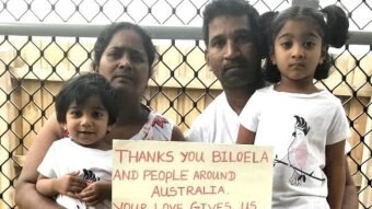 Biloela asylum seeker family, father, mother and two daughters, hold up a sign thanking the community.