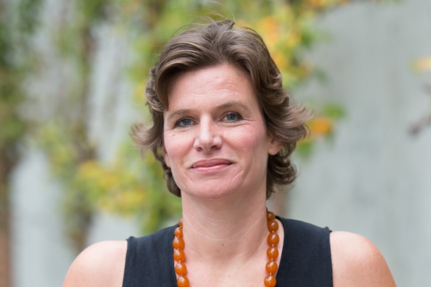 Close up of Mariana Mazzucato's face. Smiling at camera. Wearing amber necklace looking professional.