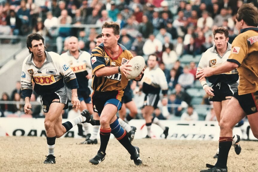 A player takes on defenders during a rugby league match. 