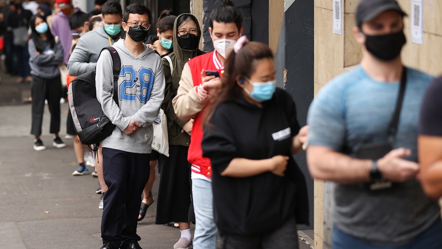 People wearing masks queue for a covid test