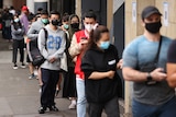 People wearing masks queue for a covid test