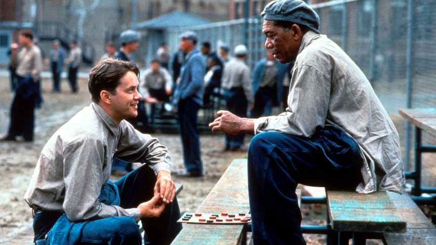 Two prisoners talk in a prison yard.