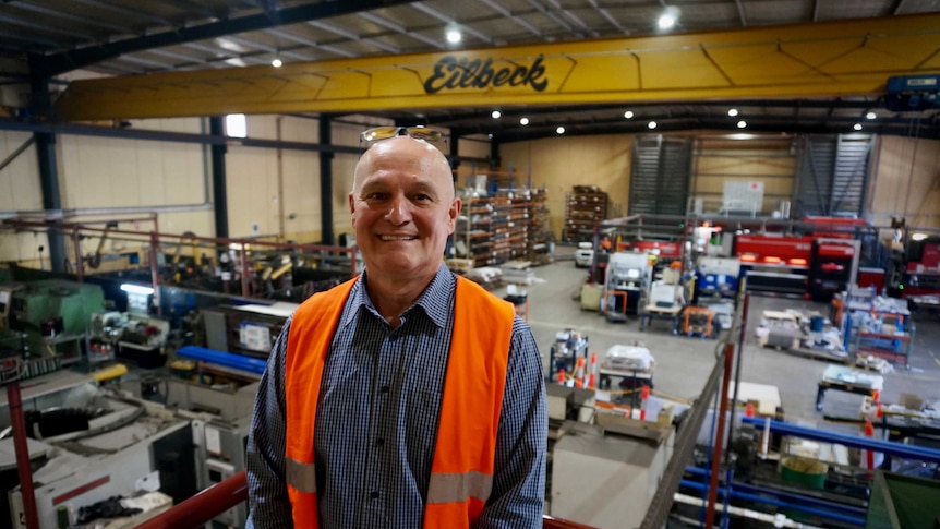 A man in hi-vis clothing standing in his warehouse.