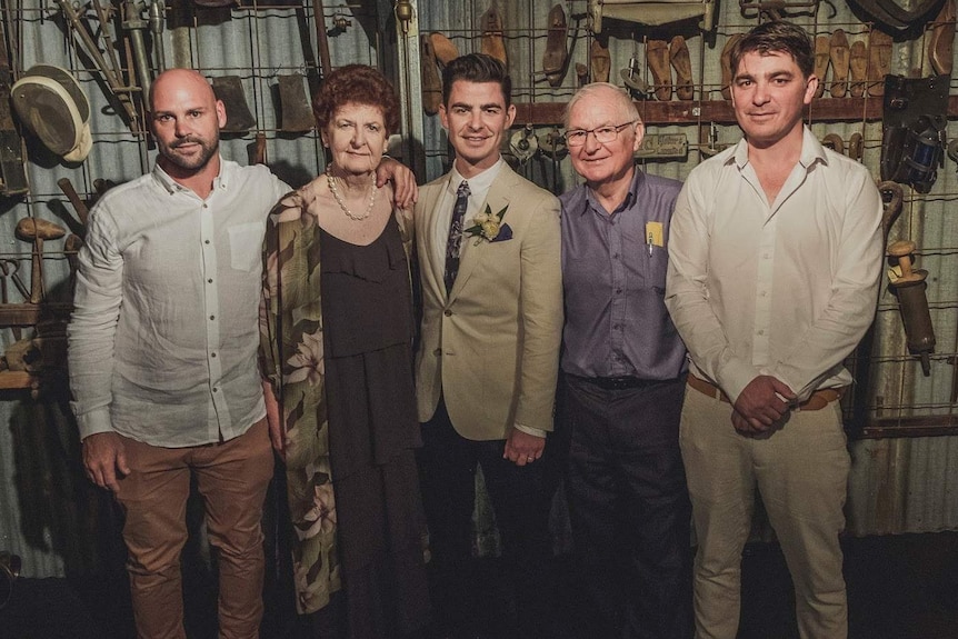 Parents and their three sons all in formal wedding attire standing in a shed.