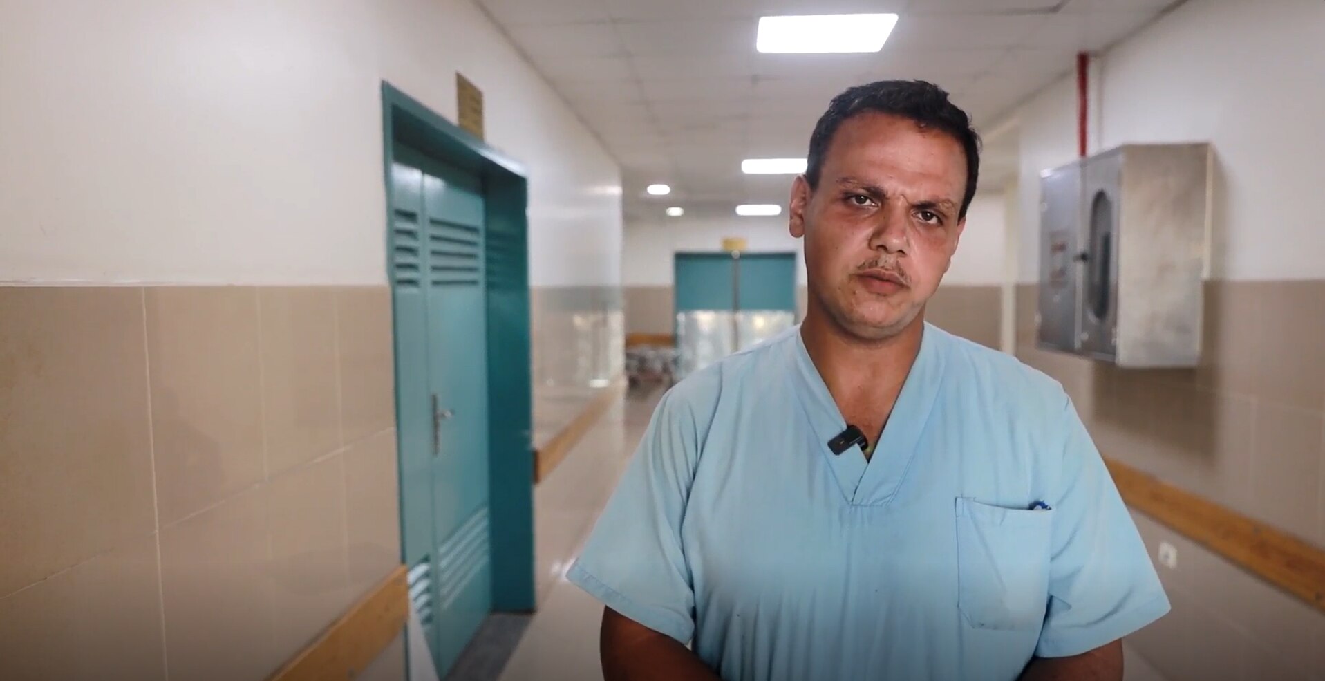 A doctor in a hospital hallway with a serious expression