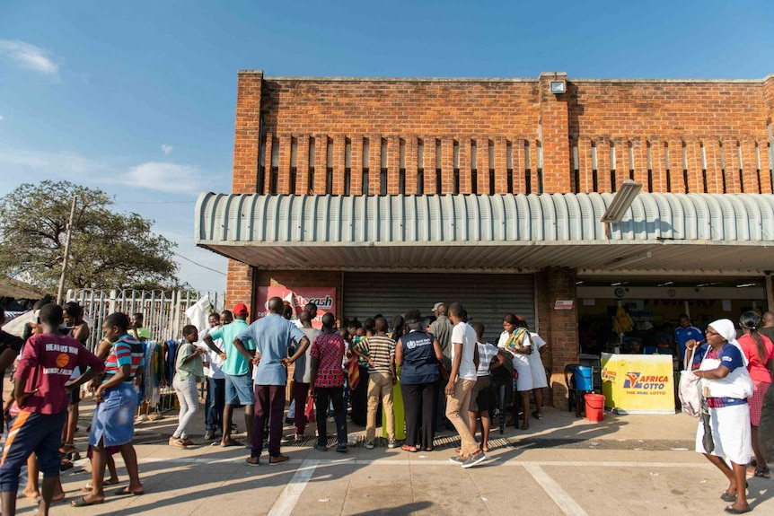 a group of people que outside of a brick building