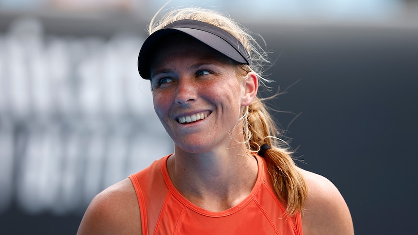 An Australian female tennis player smiles as she looks to her right.